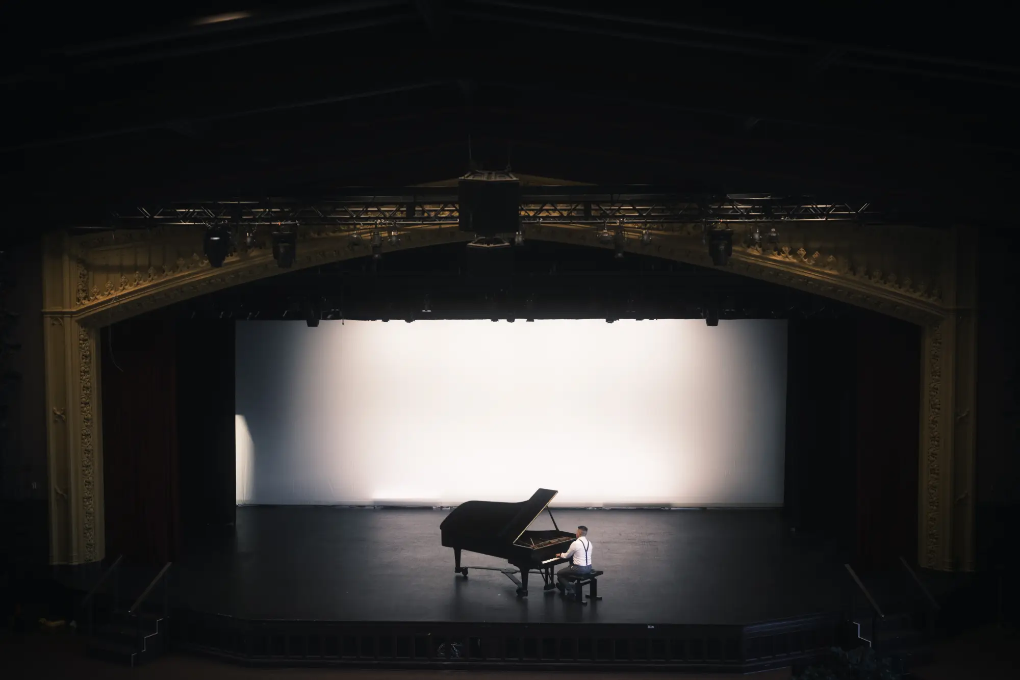 Isaac Ezekiel playing a grand piano alone on a theater stage