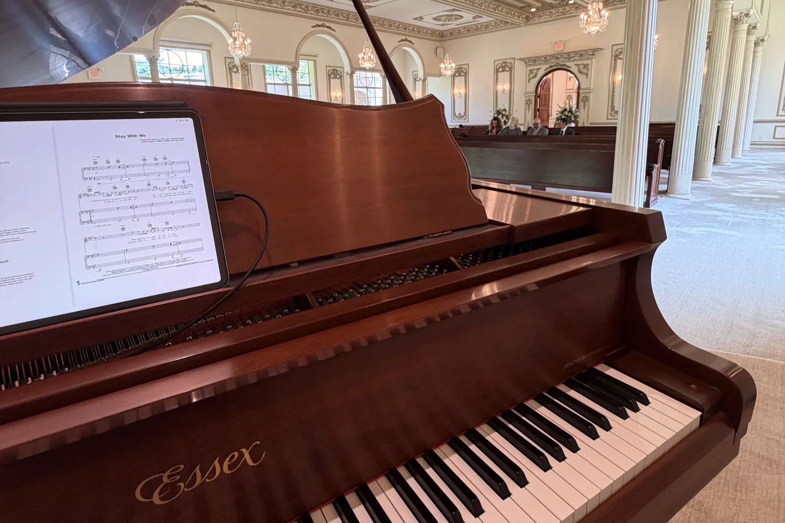 Grand piano with music on the stand in an ornate ballroom