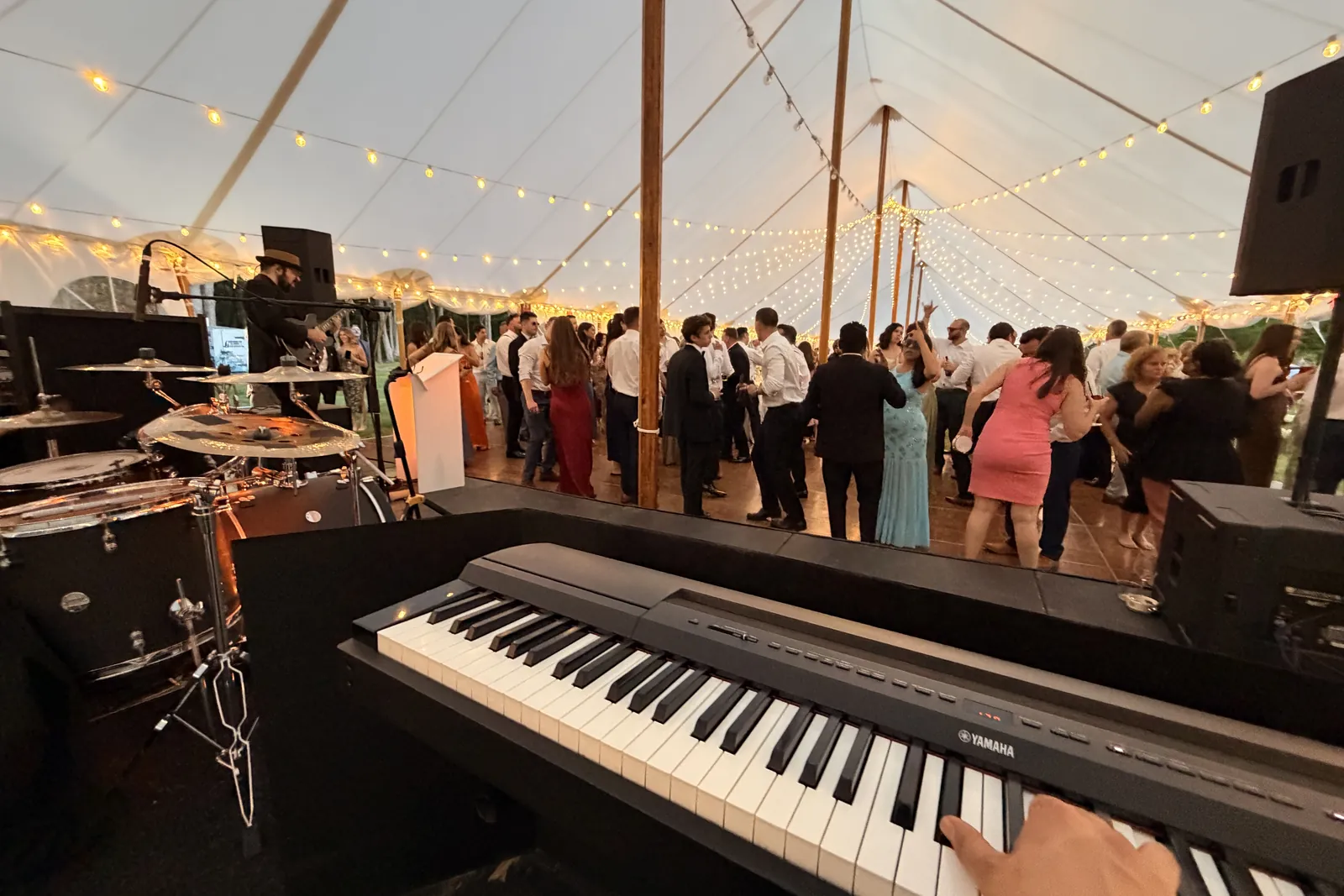 View from the keys of a packed tent reception dance floor