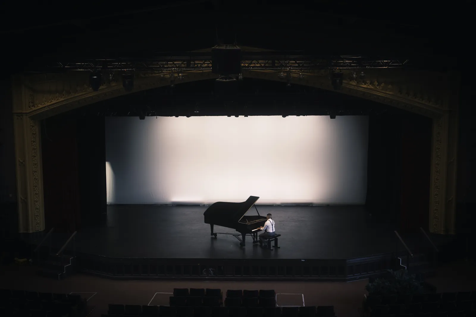 A theater seen from the balcony, Isaac at the piano center stage