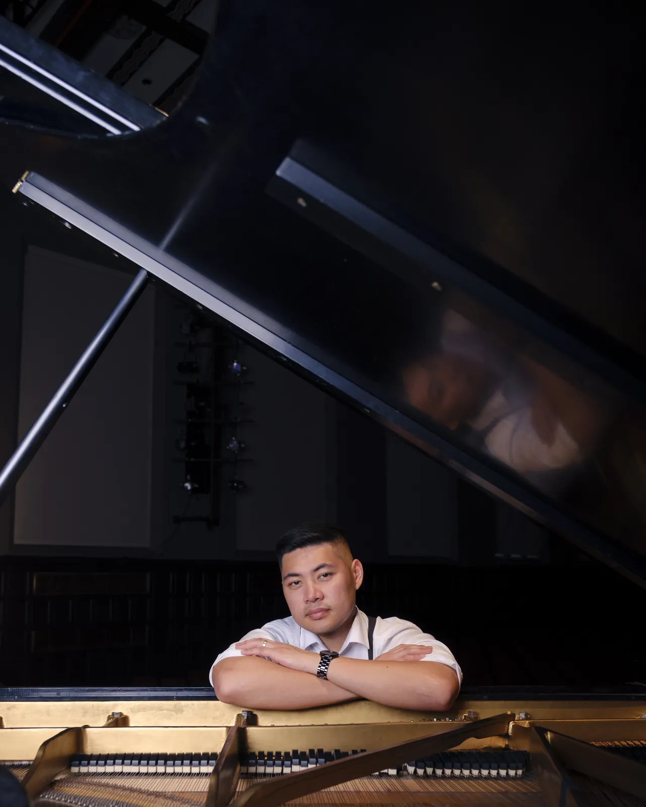 Isaac with arms crossed on the rim of an open grand piano